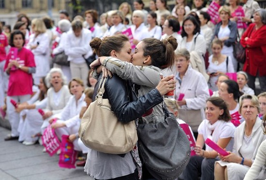 Casal de lésbicas se beija em frente a pessoas que participam de manifestação contra o casamento gay e adoções por casais do mesmo sexo, em Marselha, na França. O movimento Alliance VITA protestava contra a provável adoção de uma lei, a ser assinada no dia 31 de outubro, autorizando o casamento gay. Foto de Gérard Julien/AFP.