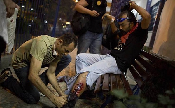 Manifestante baleado na perna recebe os primeiros socorros. Foto de Felipe Dana/Associated Press.
