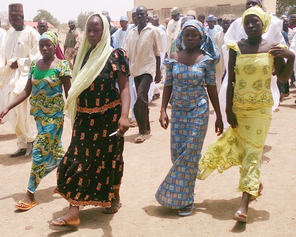 Quatro estudantes caminham em Chibok, após fugirem do grupo Boko Haram. Foto de Haruna Umar/AP.